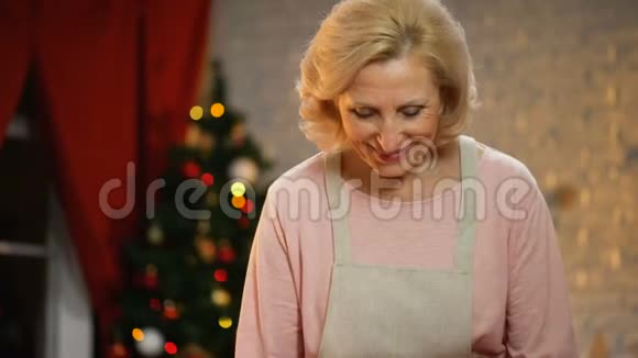 退休的女士闻烤鸡背景上的圣诞灯闪闪发光视频的预览图