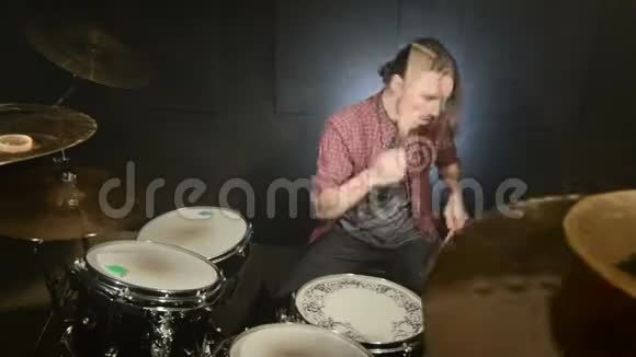 这位长发鼓手在一个黑色背景的黑暗房间里演奏完鼓摇滚音乐家静态计划视频的预览图