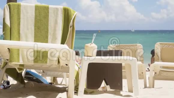 海滩上的桌子和躺椅在大海的背景下用稻草做椰子4K视频的预览图