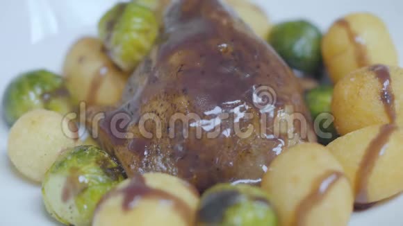 美味的鸭肉上面放着酱汁放在盘子里上面放着刚烤好的布鲁塞尔芽和奶酪球视频的预览图
