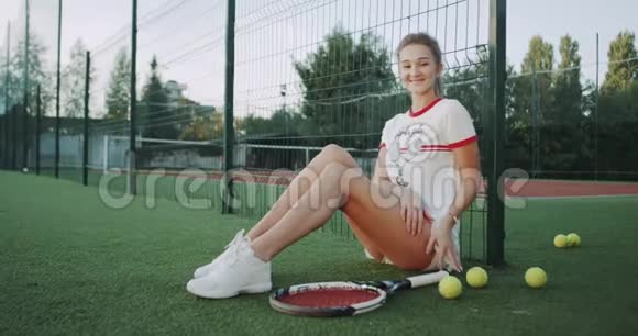 坐在地板上的职业网球运动员女性微笑着看着镜头视频的预览图