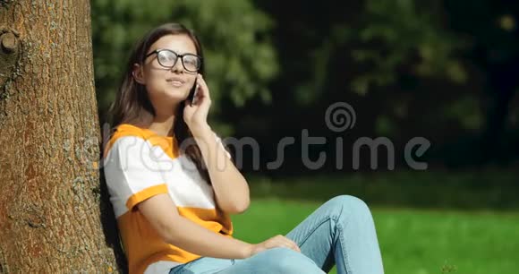 在公园里用智能手机说话的女人视频的预览图