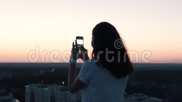 日落时女孩从屋顶拍了一张照片视频的预览图