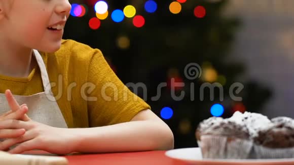 穿围裙的孩子从节日桌上偷蛋糕品尝甜点特写视频的预览图