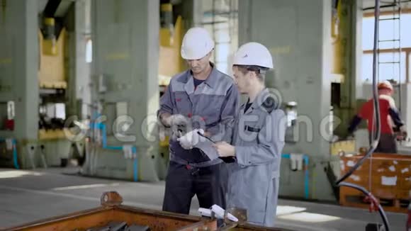 工业工人仔细看了一个工厂的船员主管新交付的金属零件视频的预览图