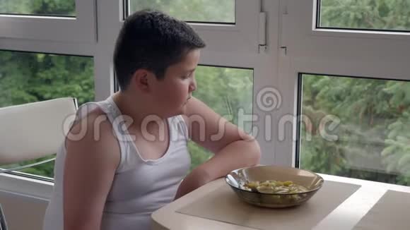 无聊的小胖子在厨房里吃饭吃一大勺汤儿童肥胖和暴饮暴食视频的预览图