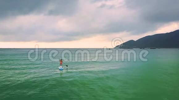 在船上冲浪的孤独女孩向后眺望大海视频的预览图