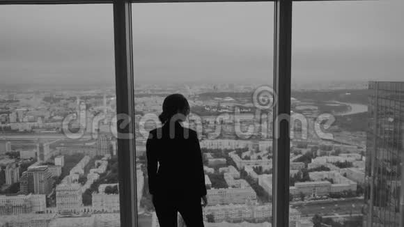 商务女性站在摩天大楼高层的一扇大窗户附近视频的预览图