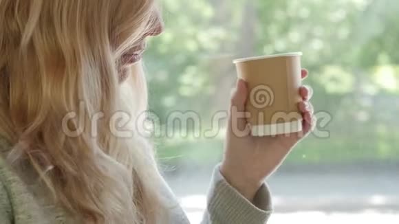 特写的金发女郎从纸杯里喝茶去喝咖啡视频的预览图