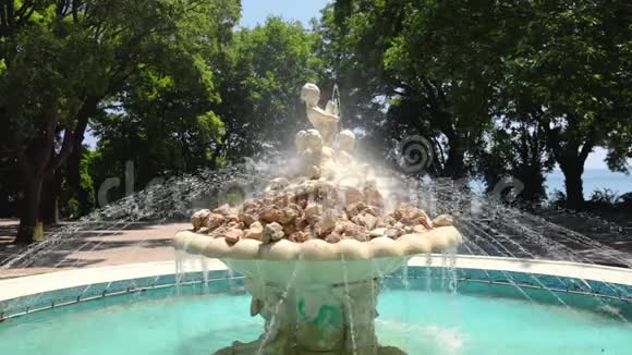 在保加利亚瓦尔纳的海洋花园公园里有天使雕像的喷泉周围有青草和树木视频的预览图