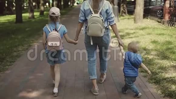 一位快乐的母亲在公园里散步时牵着孩子的手视频的预览图
