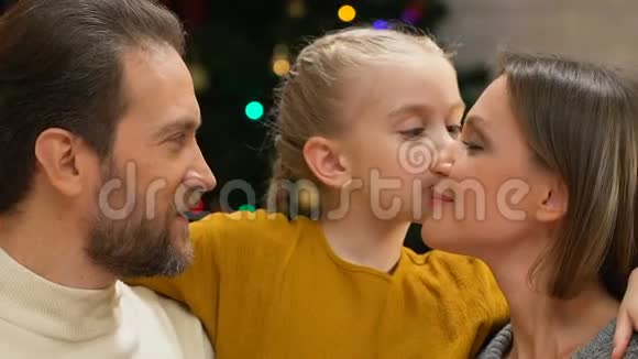 女孩亲吻爸爸妈妈的脸颊向家人表达爱和关怀视频的预览图