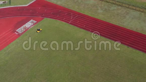 黄色割草机割草球场足球绿草地空中视频的预览图