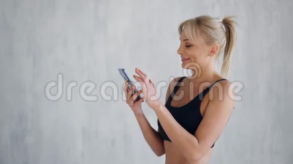 快乐的年轻体育女性展示智能手机绿色屏幕视频的预览图