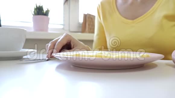 坐在餐桌旁的女人准备在家或餐馆吃一个小面包喝咖啡或茶作为早餐视频的预览图