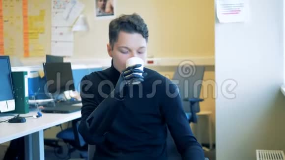 一个拥有人工仿生未来派手的年轻人正从杯子里喝酒未来概念的人视频的预览图