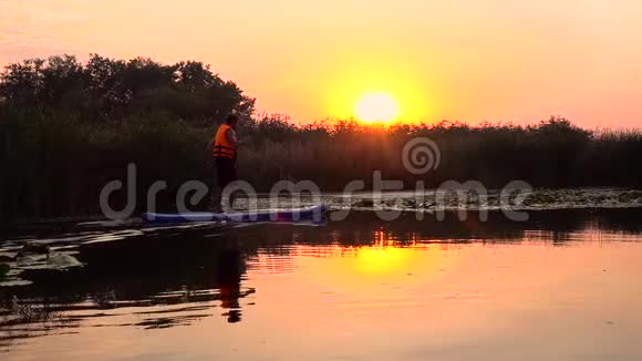 人们站在充气筏上划桨板进入日落慢动作视频的预览图