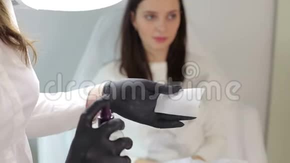 戴着黑色手套的美容师把无菌溶液溅到餐巾上视频的预览图