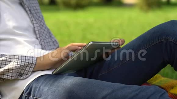 在夏季公园的平板电脑工作的男性自由职业者学生在线求职视频的预览图