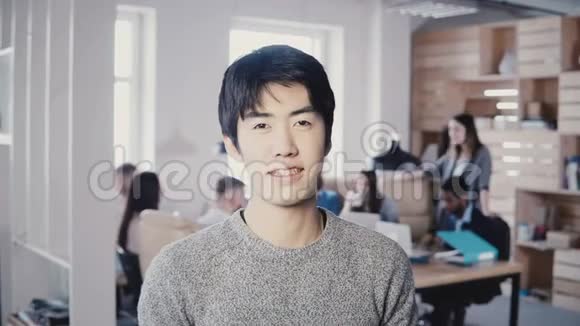 年轻成功的亚洲商人在繁忙的办公室微笑的肖像英俊的男经理看着相机摆姿势4K视频的预览图