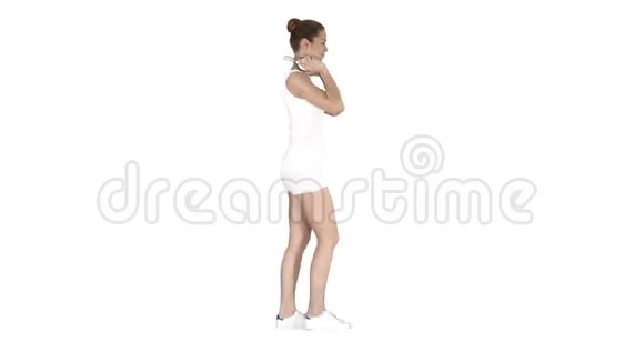 穿白衬衫的女人用耳机听音乐走在白色背景上视频的预览图