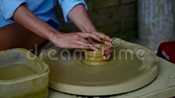 在陶器店里特写女孩用陶轮做陶罐视频的预览图