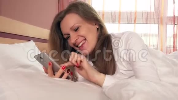 年轻笑脸女子用智能手机上网聊天视频的预览图