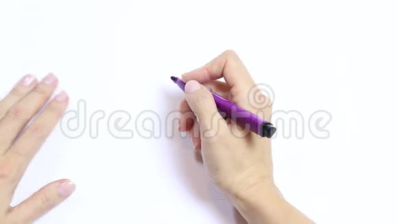 女人用手在白色的桌子上画了一座带有紫罗兰色记号的房子视频的预览图