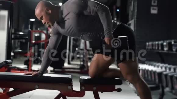 肌肉男在健身房进行运动训练哑铃在背部肌肉上做运动视频的预览图