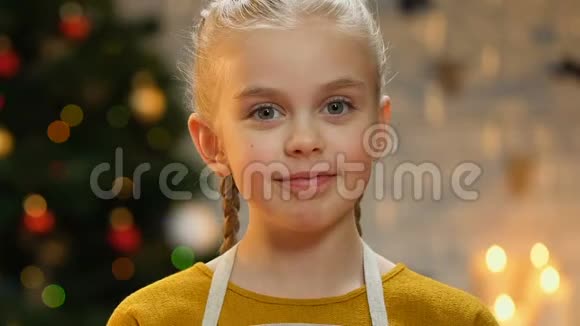 穿着围裙的小女孩对着镜头展示蛋糕为自制的糕点感到骄傲视频的预览图