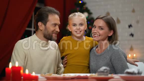 父母亲吻微笑的女儿圣诞装饰闪闪发光肖像效果视频的预览图