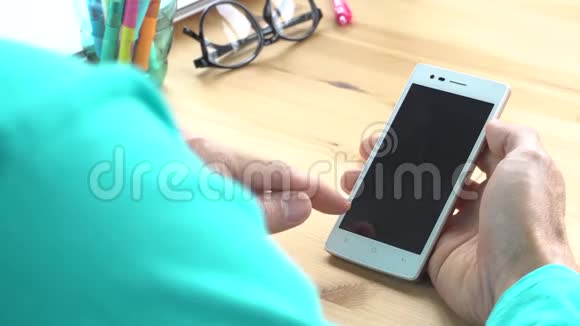 商务人员穿绿色t恤滑动缩放触摸智能手机在家庭办公室水平视频的预览图