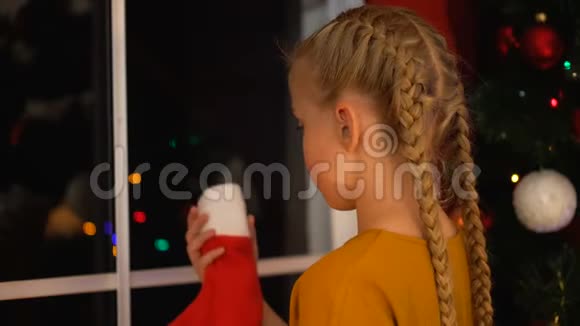 一个被遗弃的小女孩在一只袜子里放糖果准备礼物圣诞前夜视频的预览图