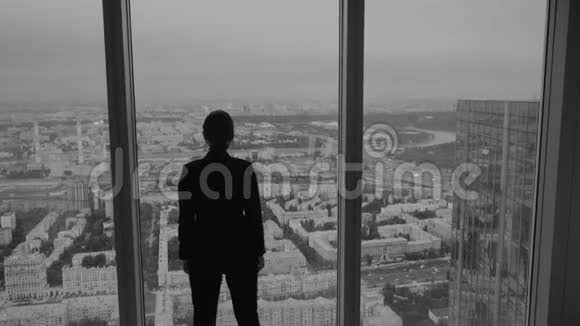 商务女性站在摩天大楼高层的一扇大窗户附近视频的预览图