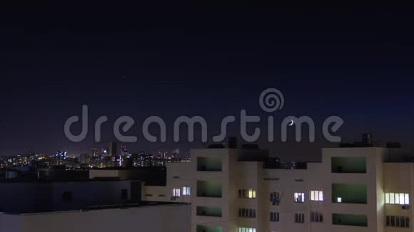 夜城时光流逝星星和新月亮在天空上移动住宅公寓的窗户亮起并关闭城市天际线视频的预览图