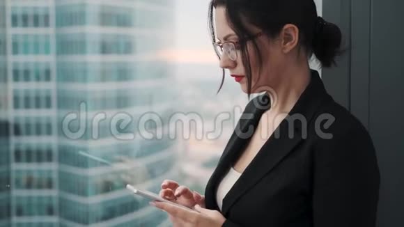 商业女性的特写肖像手里拿着一部智能手机一个穿着商务服的女人站在一个大个子旁边视频的预览图