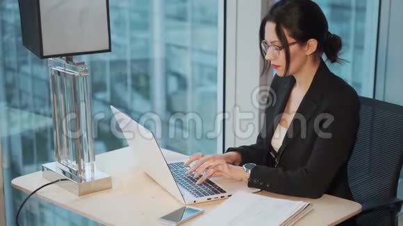 商务女性坐在办公室的窗户旁用电脑工作一位身着商务服装的年轻女子的肖像视频的预览图
