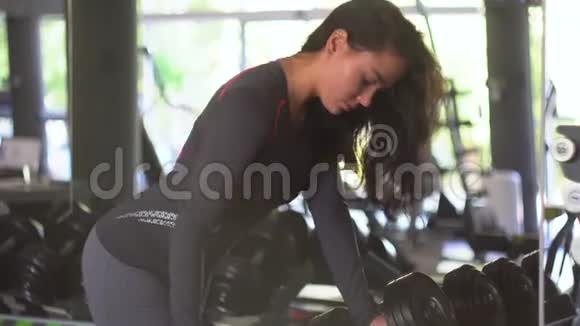 年轻健身女子在健身房用哑铃锻炼视频的预览图