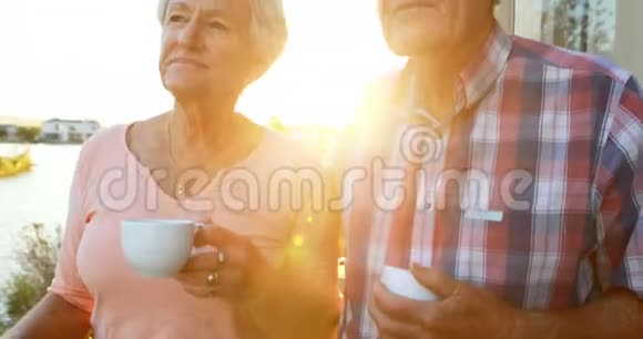 有咖啡杯的老夫妇站在4k阳台视频的预览图