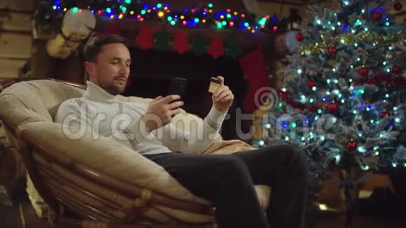 圣诞之夜快乐的成人通过智能手机和信用卡在网上购物视频的预览图