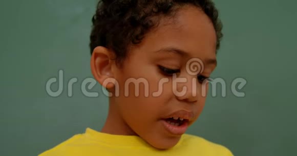 4k教室里非裔美国小学生靠绿色黑板站立的特写镜头视频的预览图