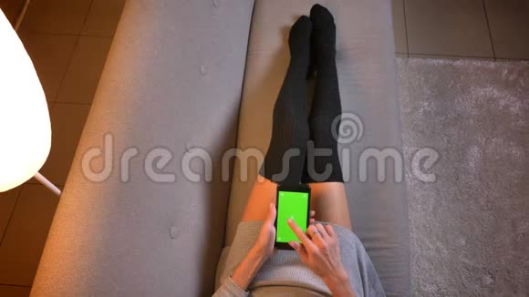 使用绿色屏幕的手机社交媒体拍摄年轻有吸引力的女性食品博主的特写镜头女孩的腿视频的预览图