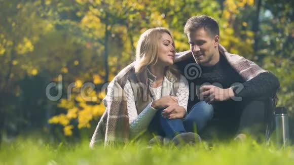 坐在秋天公园里的一对夫妇喝着热茶说话视频的预览图