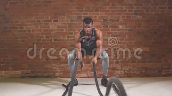 英俊的肌肉裸露的胸部健身男子正在做战斗绳锻炼慢动作视频的预览图
