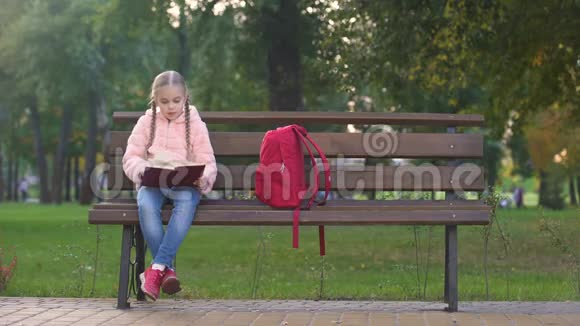 聪明的女孩在公园的长椅上看书智力爱好花空闲时间视频的预览图