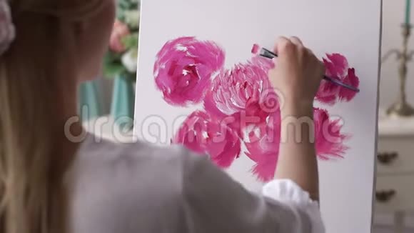 一个年轻的创意女孩在画室的白色画布上画花视频的预览图