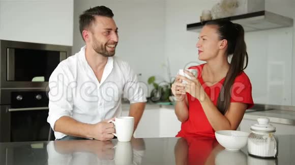 可爱的年轻夫妇在厨房里喝咖啡他们今天早上心情不错视频的预览图