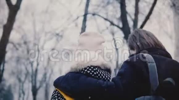 后景快乐轻松白种人年轻浪漫的情侣穿着休闲的冬装一起散步拥抱在下雪的日子视频的预览图