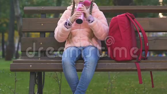 女学生从热水瓶喝茶放学后在公园吃零食健康食品视频的预览图