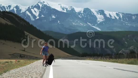 年轻的游客搭便车的女人拖着背包把背包扔在50fps的山路上视频的预览图